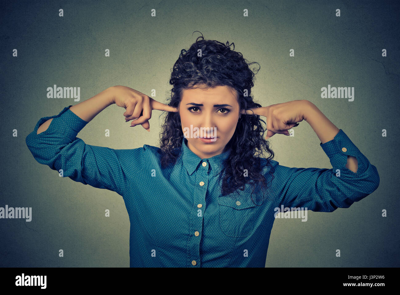 Closeup portrait upset woman plugging ears with fingers doesn't want to listen Stock Photo