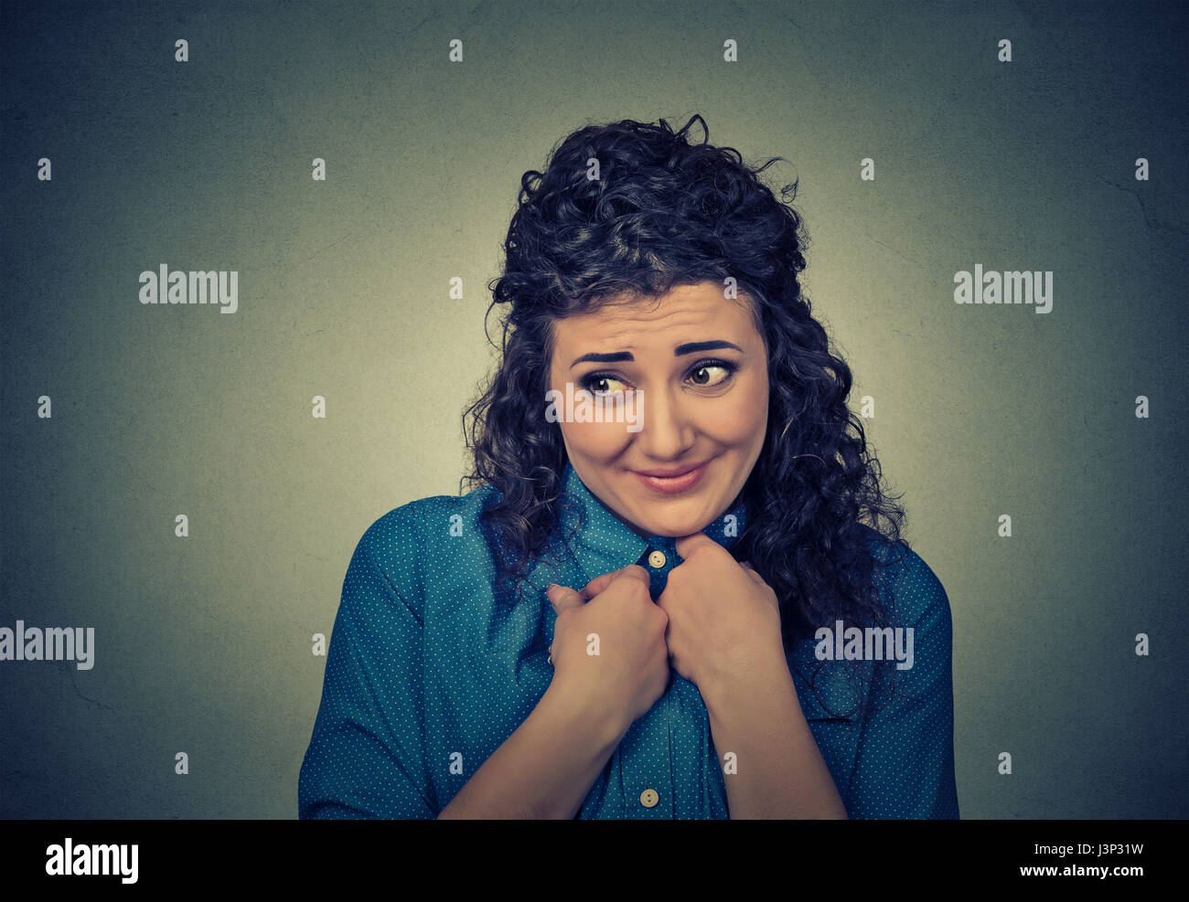Lack of confidence. Shy young woman feels awkward isolated on gray