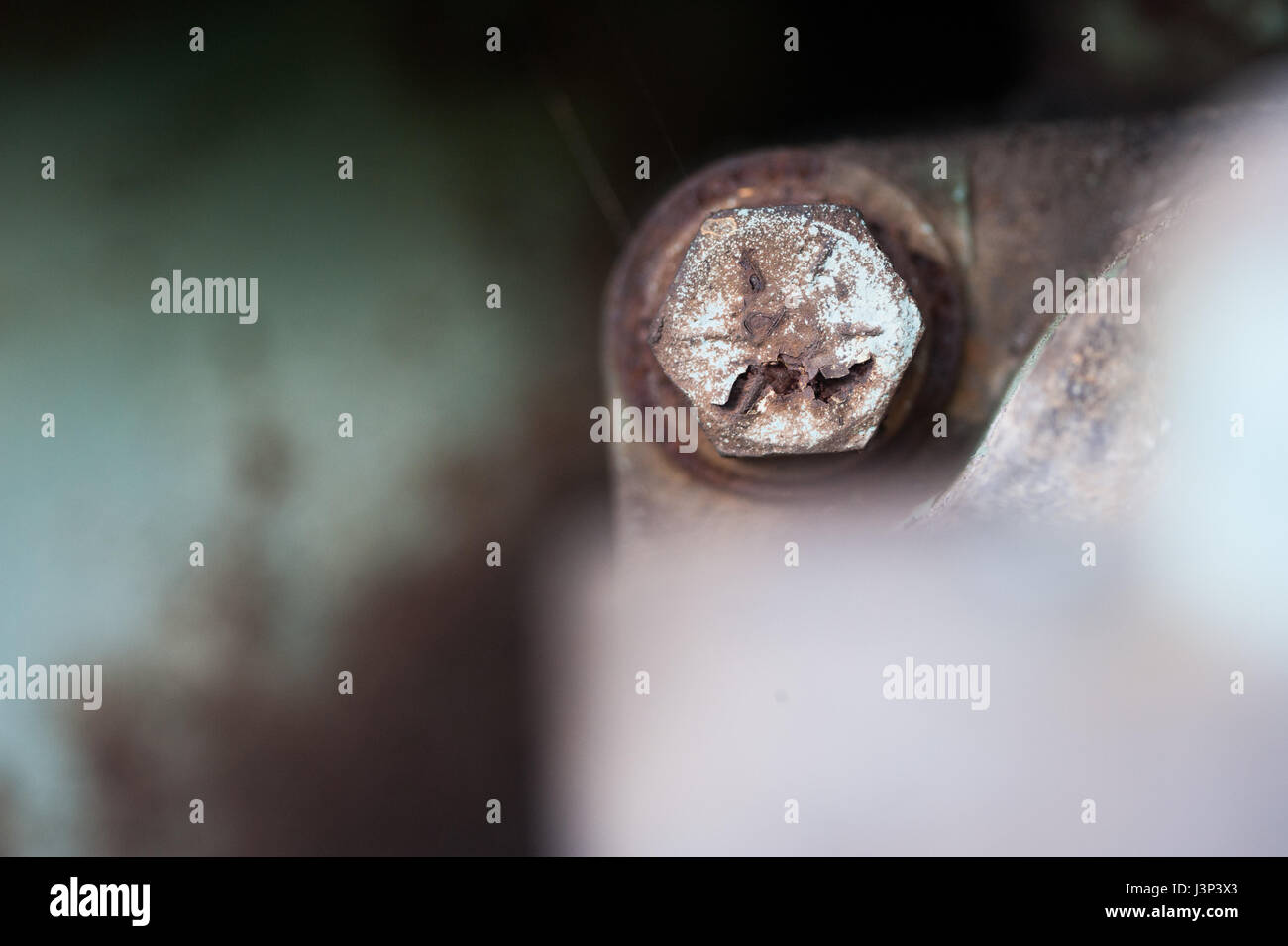 Detail of the bolt head of a rusted and peeling bolt in the engine of