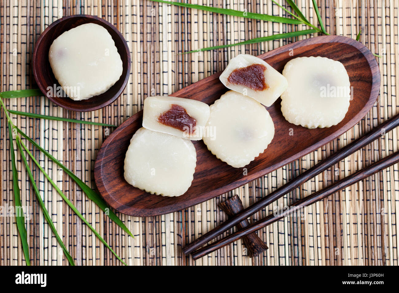 Mochi cake with red beans on wooden plate with bamboo leaves