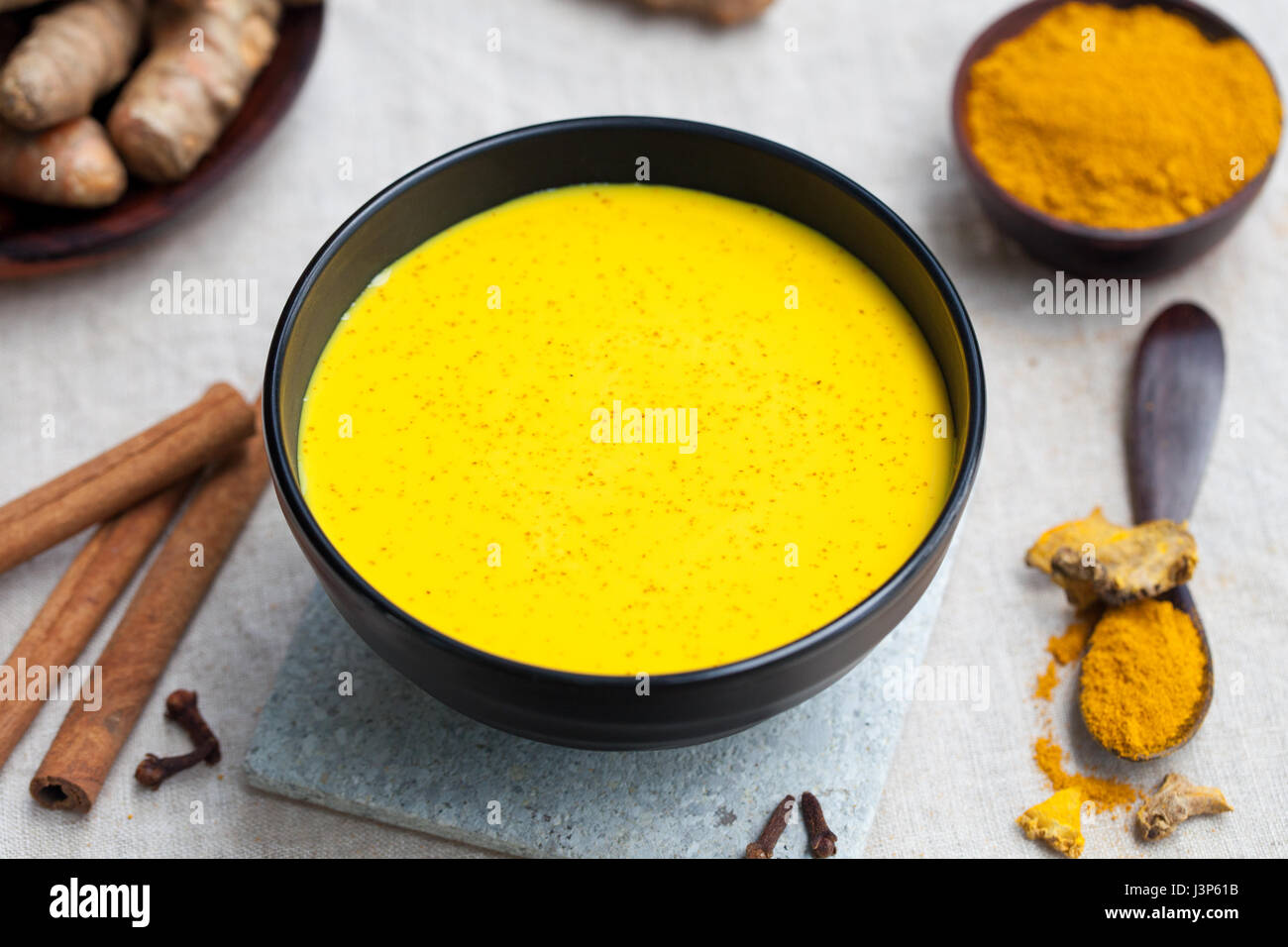 Turmeric drink, latte, tea, milk with cinnamon with fresh and dried turmeric on a textile grey