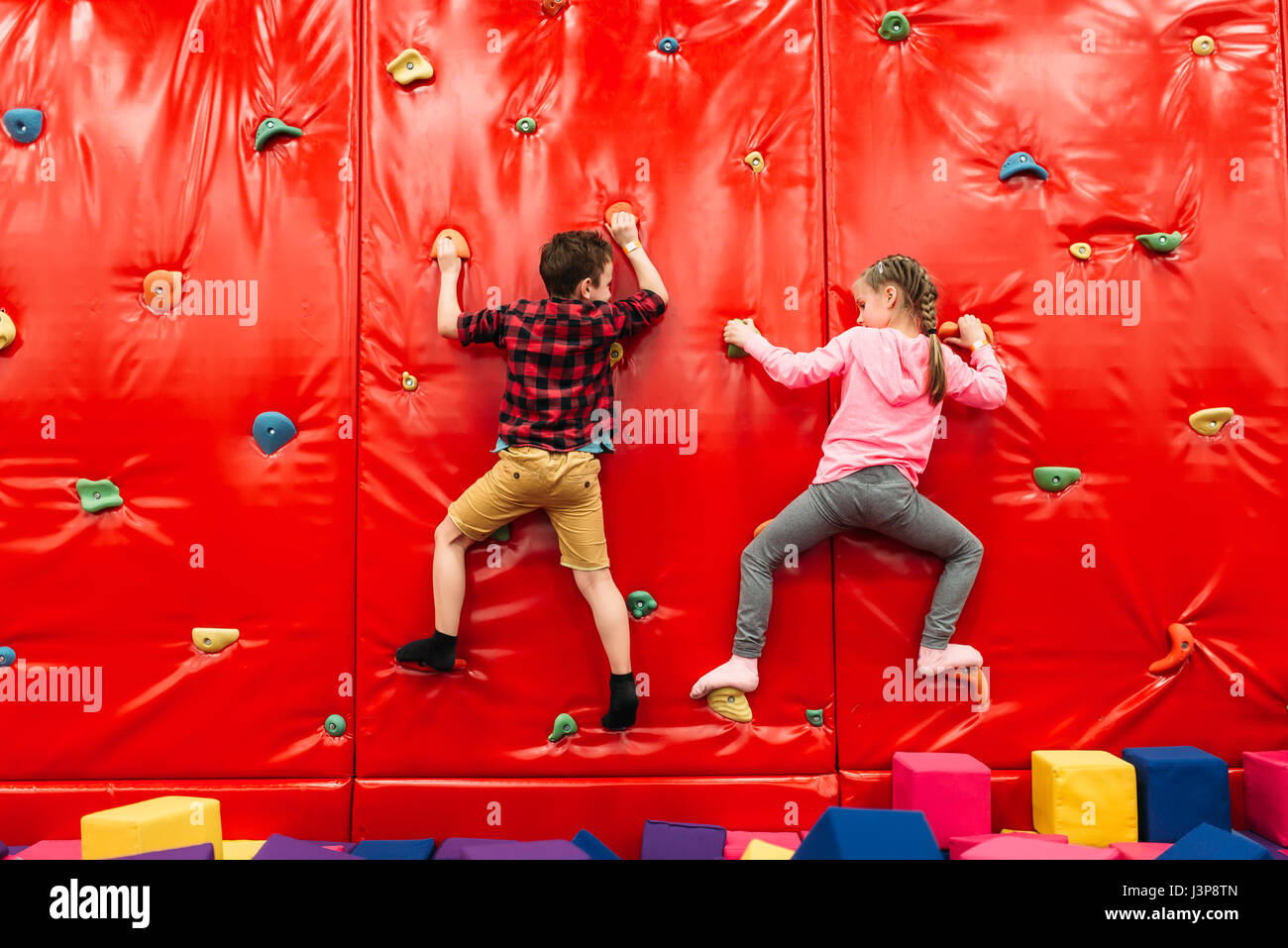 Active kids climbing on a wall in childrens attraction playground. Entertainment center. Happy childhood Stock Photo