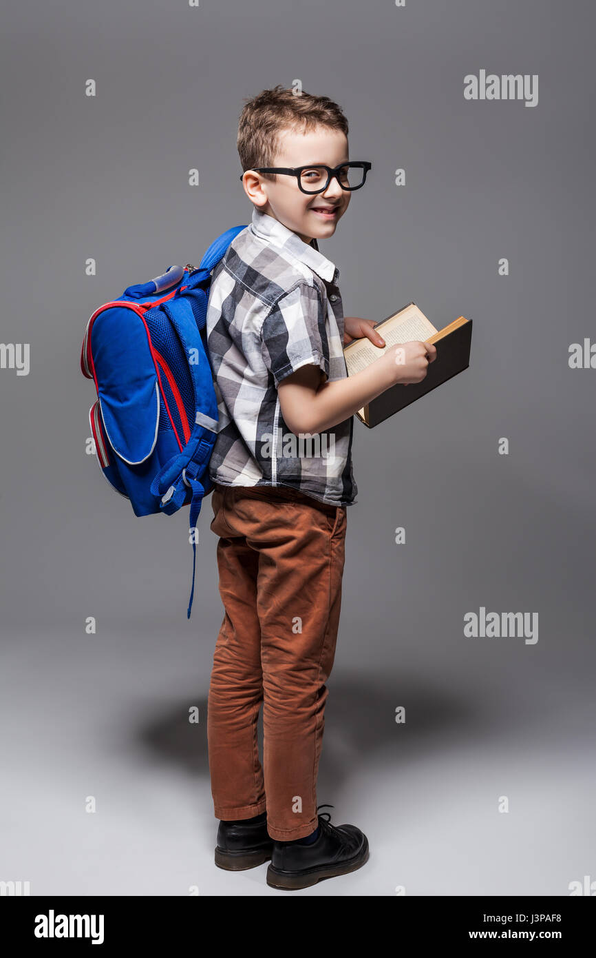 Little child with school bag and book, studio photo shoot. Young pupil ...