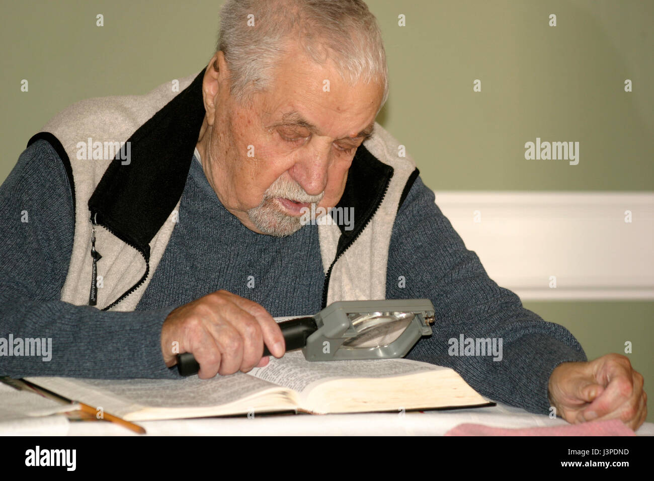 Old man reading with magnifying glass Stock Photo