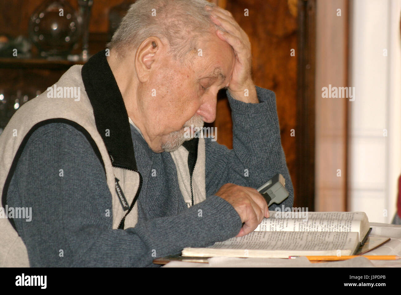Old man reading with magnifying glass Stock Photo