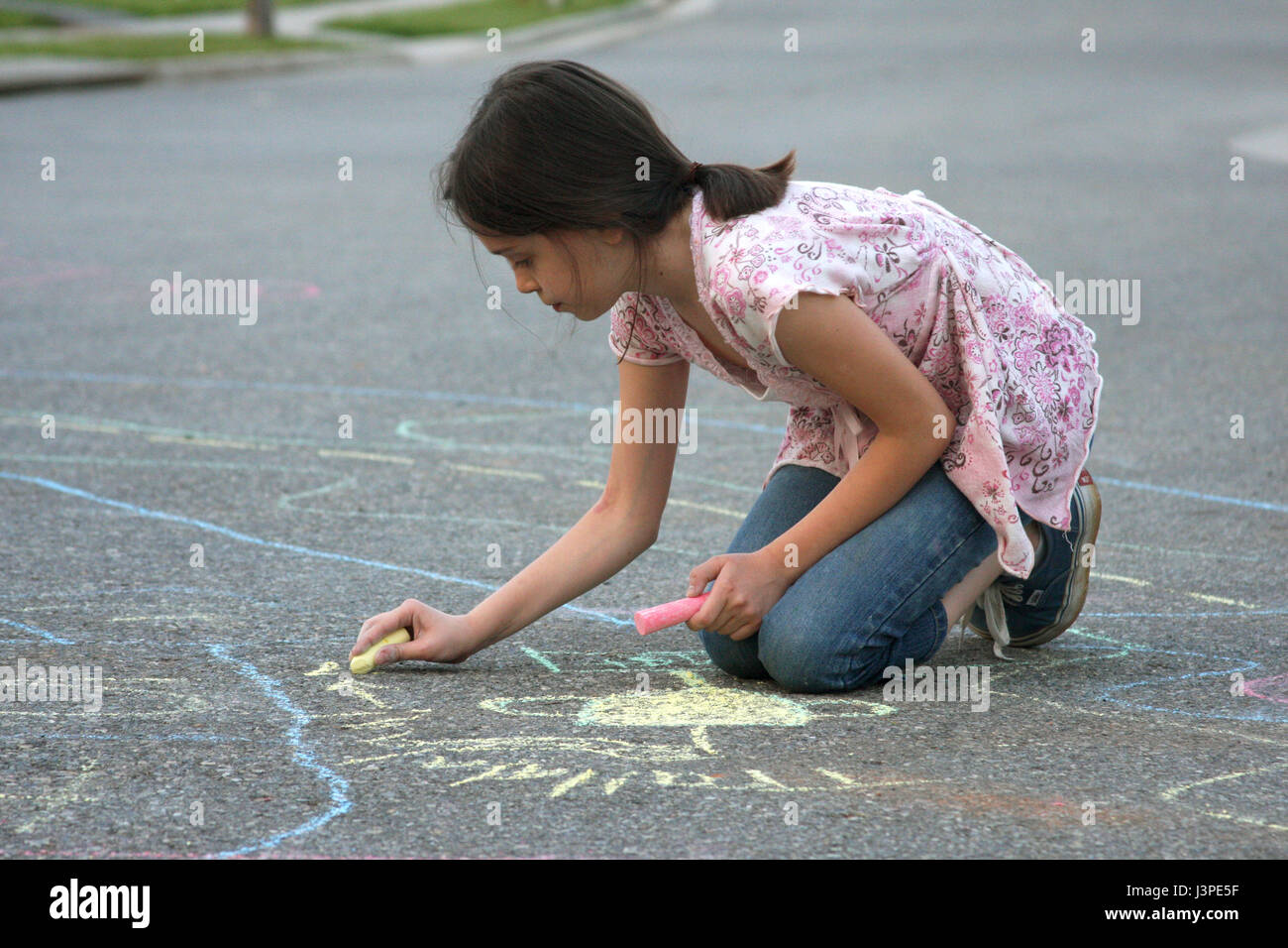 Little girl drawing with chalk on pavement Stock Photo Alamy