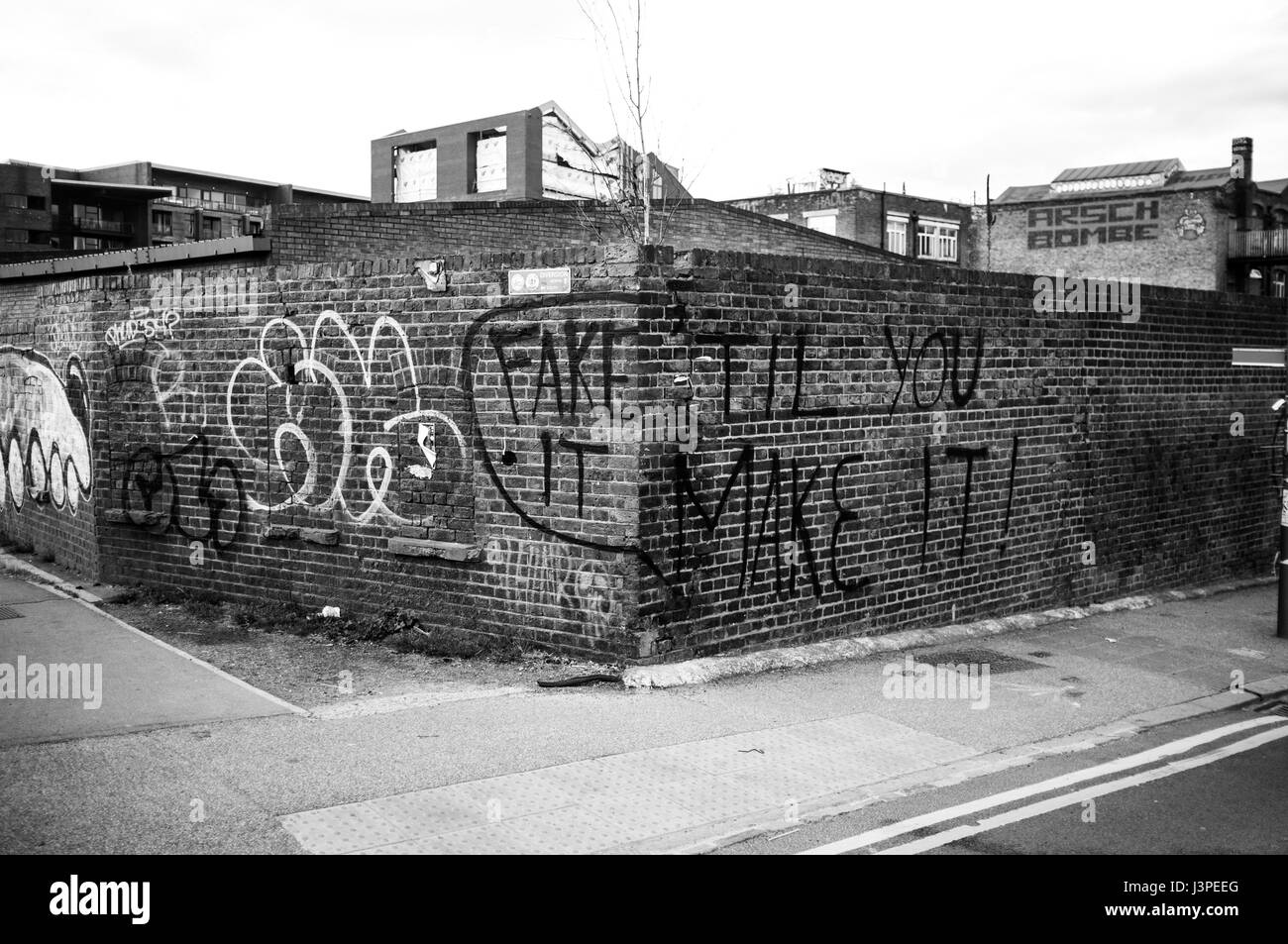 Corner of streets in Hackney Wick with graffiti saying 'Fake it 'til you make it' scrawled across. Stock Photo
