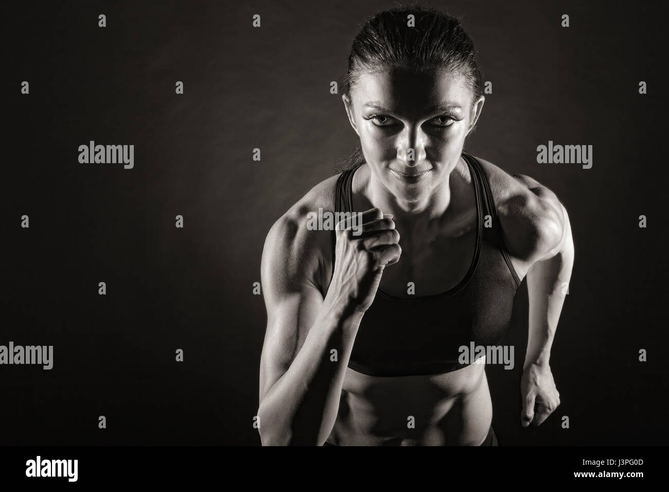 Woman running on a dark background. Front view Stock Photo