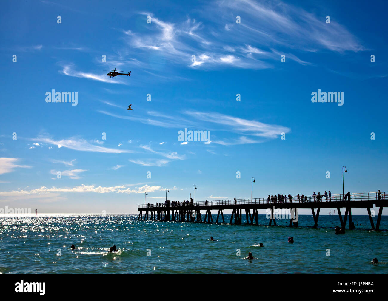 Helicopter and seagull fly over Glenelg jetty Stock Photo
