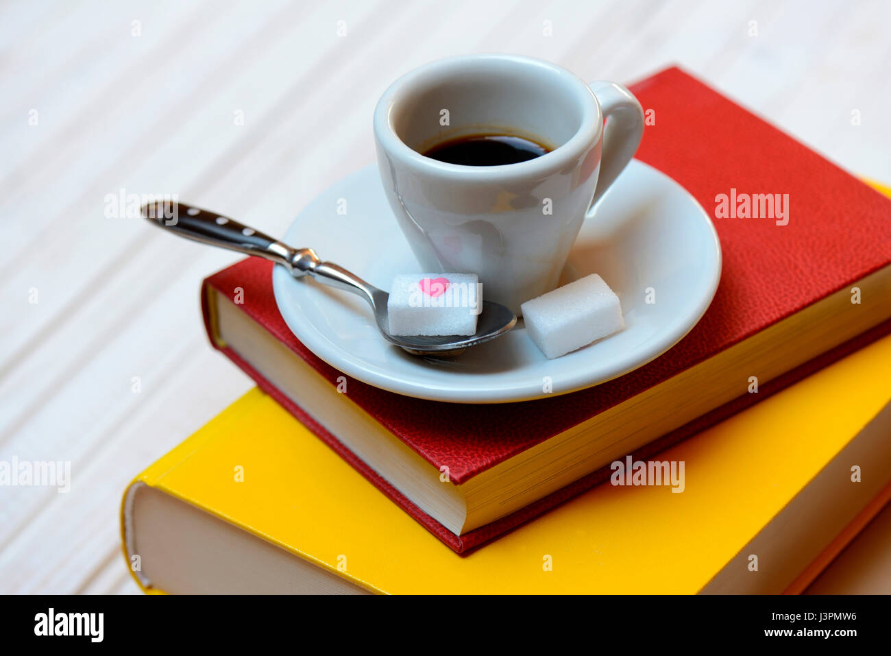 Kaffeetasse auf Buecher und Kaffeeloeffel mit Wuerfelzucker, Espresso Stock Photo