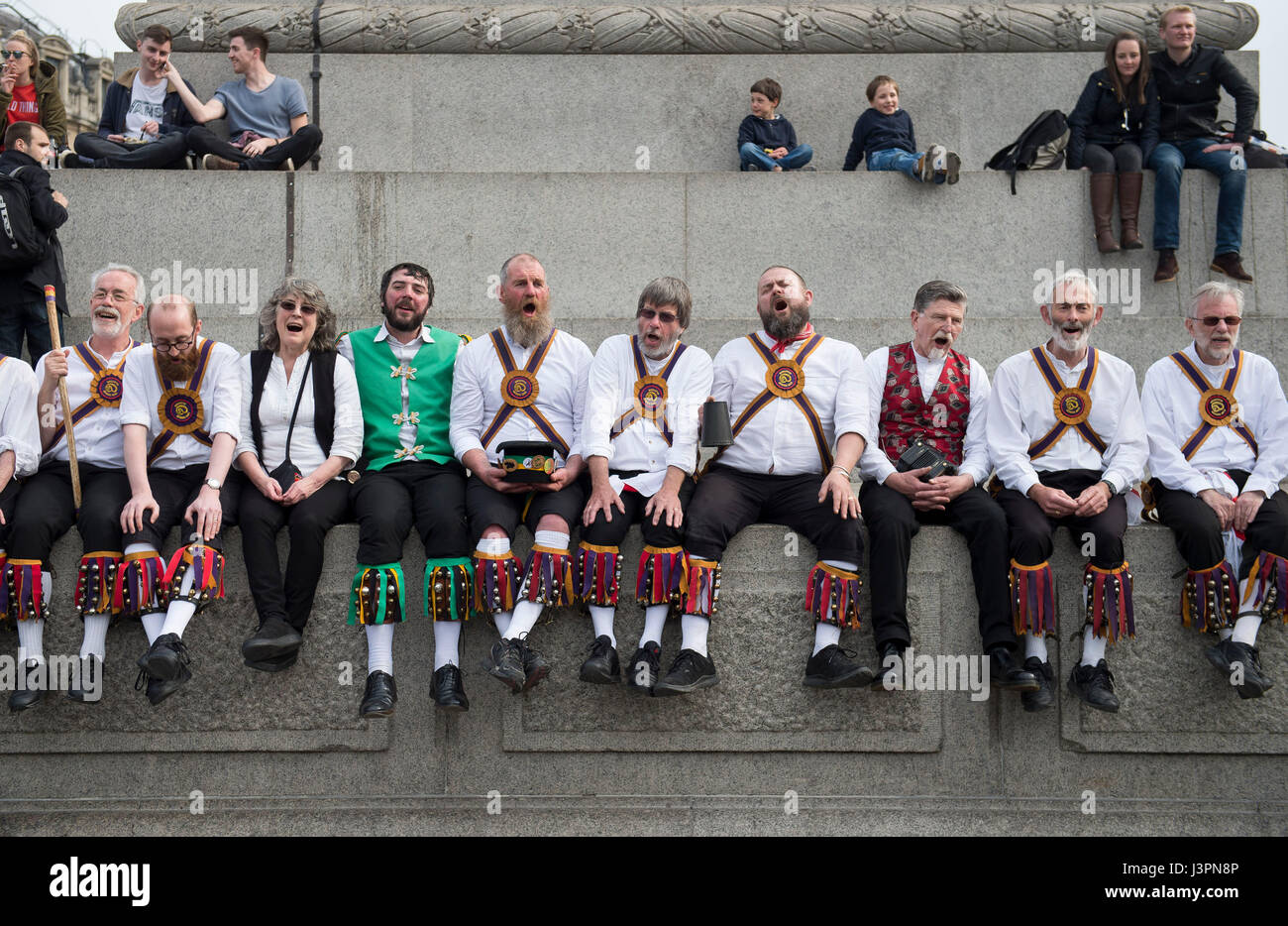 Morris dancers sit below Nelson's Column during the Westminster Morris Men's annual Day of Dance in Trafalgar Square, London, featuring Morris dancing teams from across England. Stock Photo