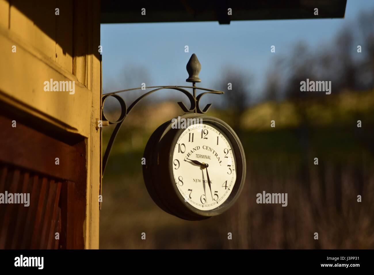 Vintage outdoor wall clock hang on the cabin with hill in the background Stock Photo