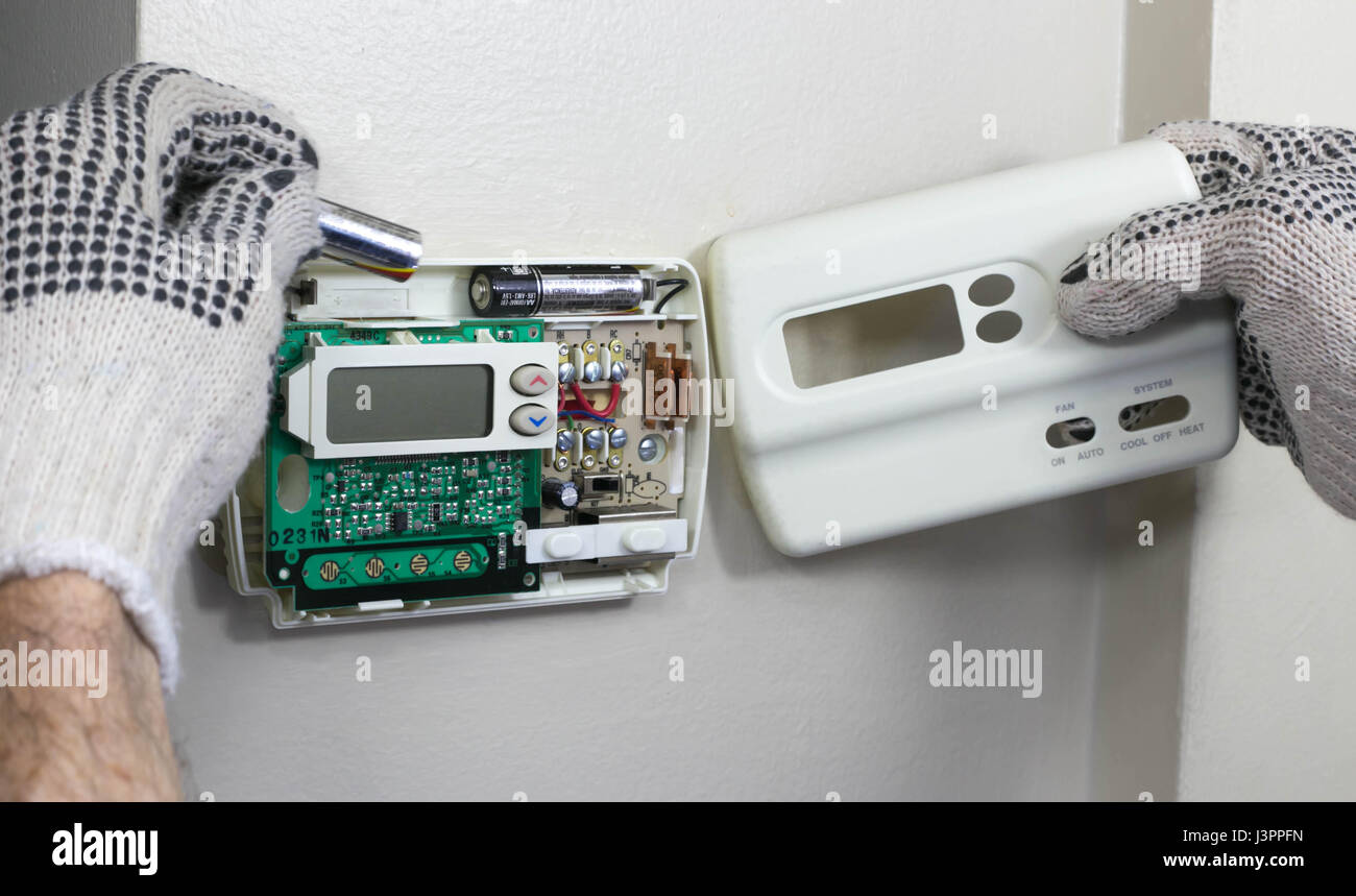 HVAC Technician Installing Batteries in Thermostat Stock Photo