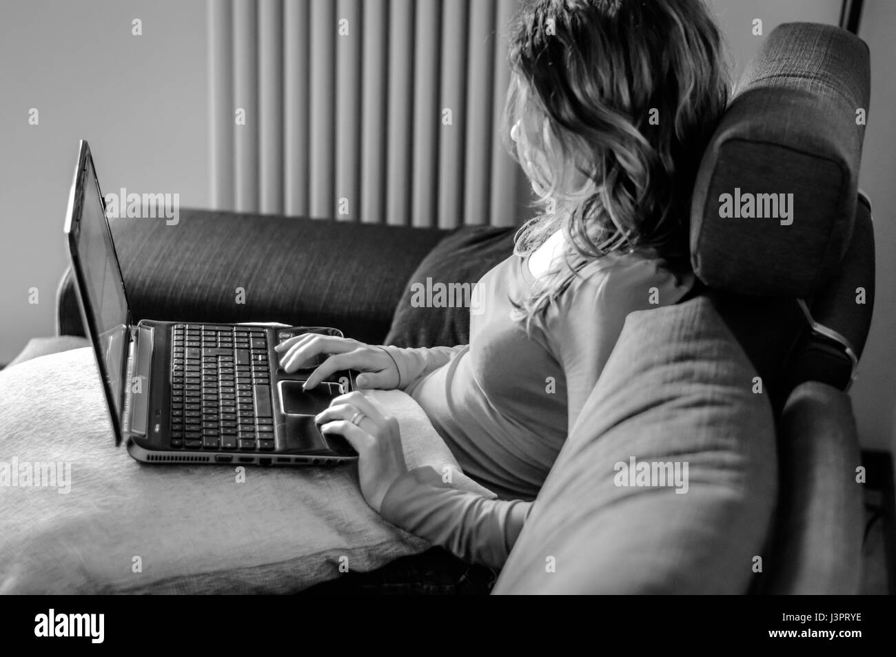young woman working on laptop on the couch, black and white image Stock Photo