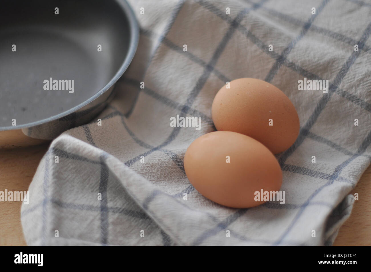 Two brown eggs over a kitchen cloth and a frying pan Stock Photo