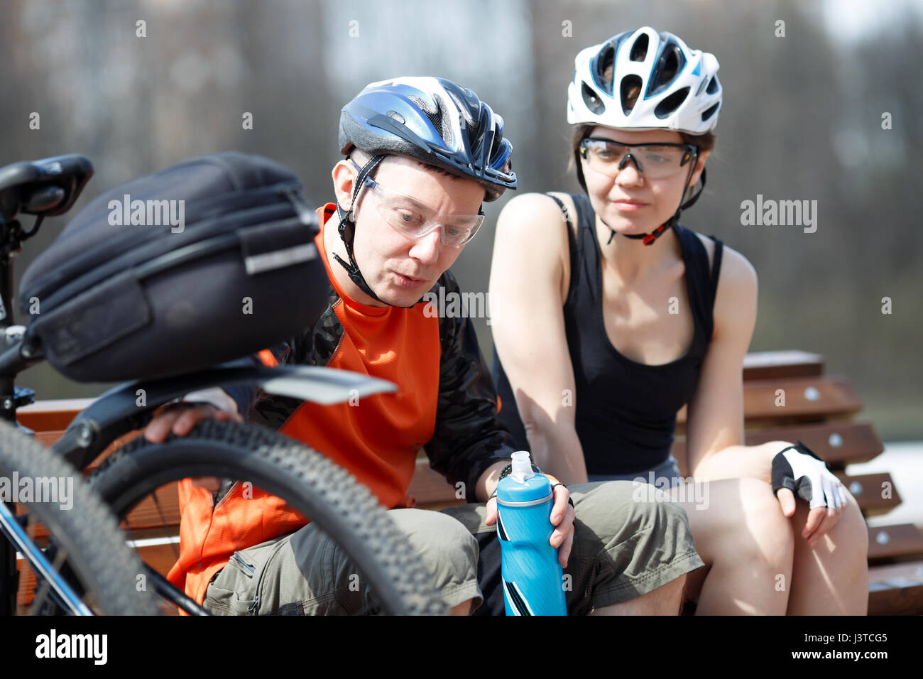Two bikers rest on bench Stock Photo - Alamy