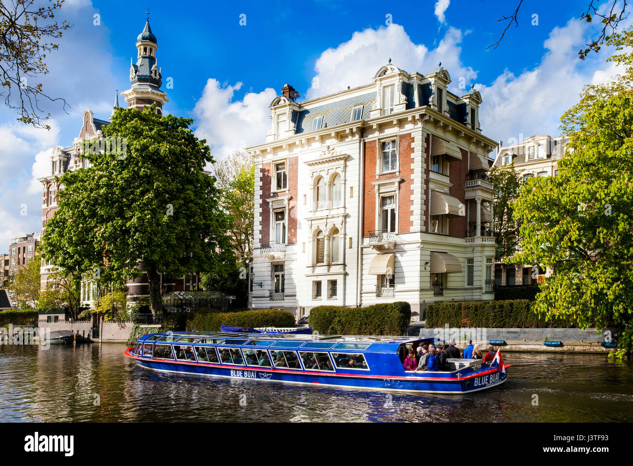 Blue boat company canal trip in Amsterdam city, Netherlands Stock Photo