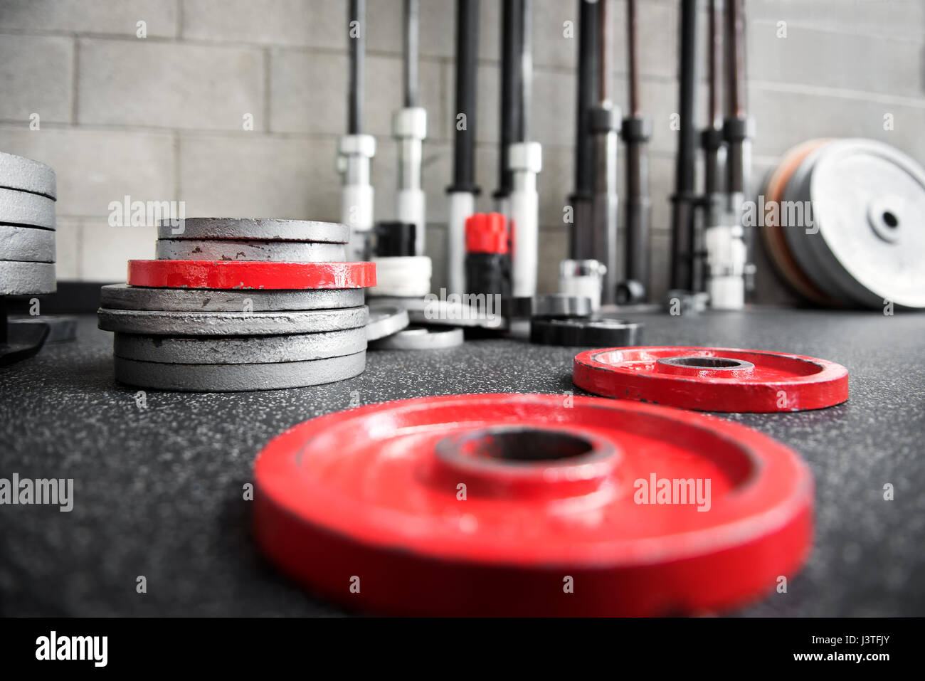 Scattered barbell weights of assorted sizes on the floor of a gym viewed low angle in a health