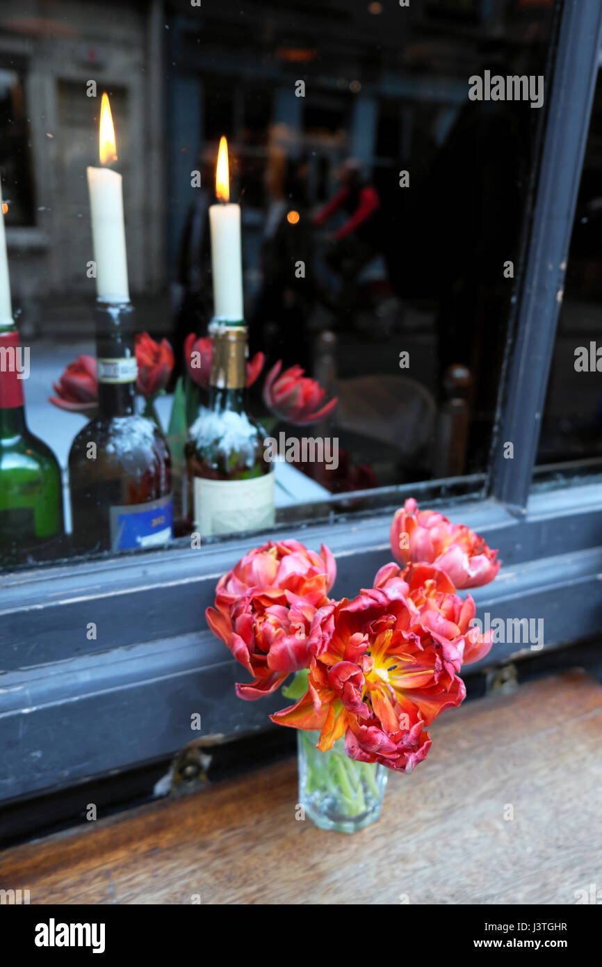 Lighted candles in wine bottles and flowers on table at Andrew Edmunds restaurant in Lexington Street, Soho, London  KATHY DEWITT Stock Photo