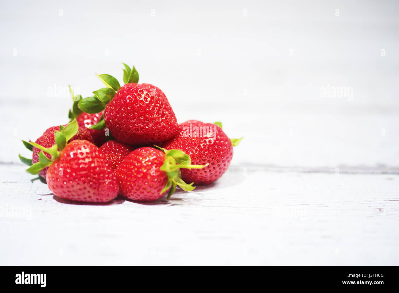 close-up strawberries on white wood background Stock Photo - Alamy