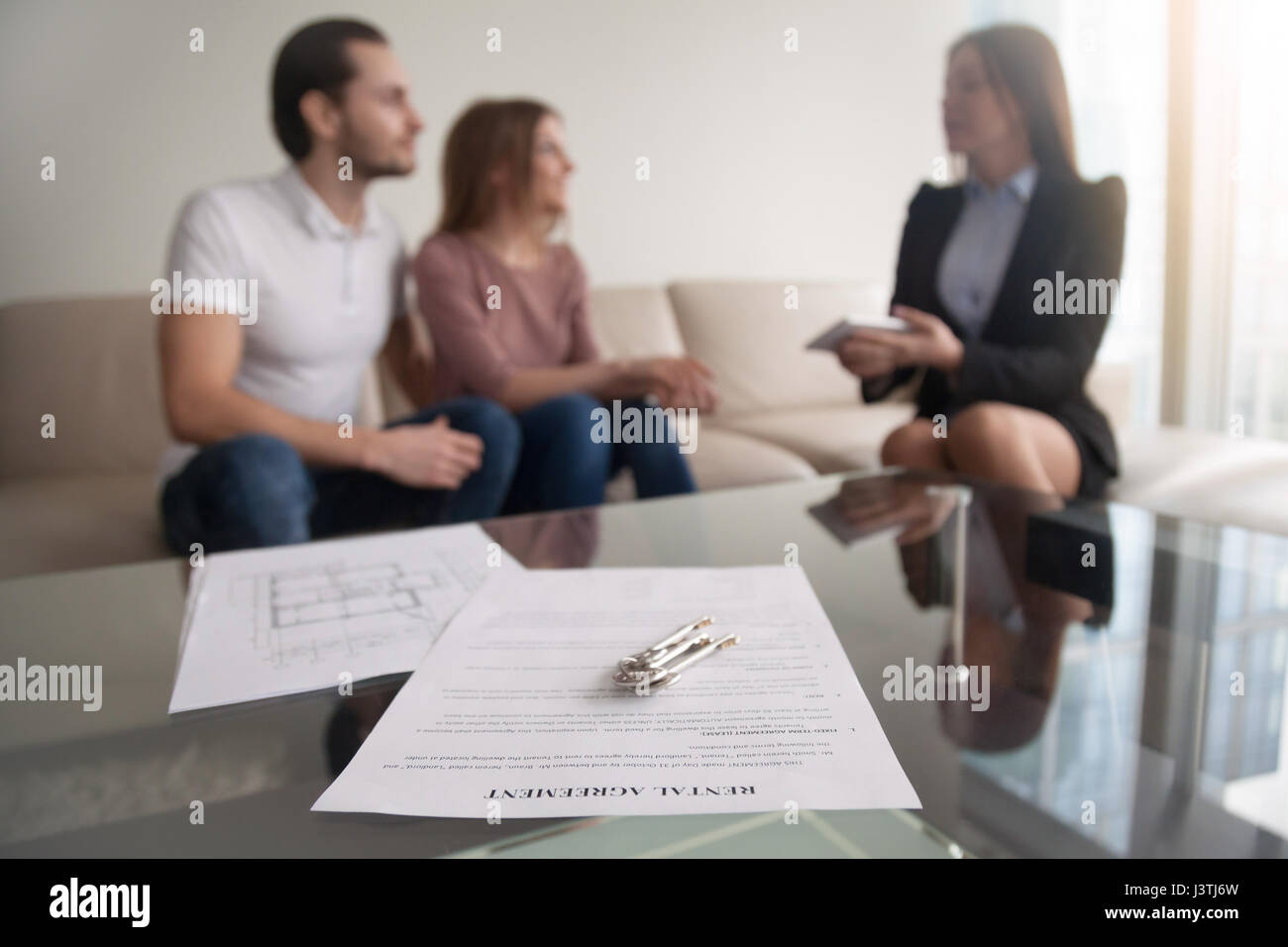 Couple meeting with realtor, focus on rental agreement and keys Stock Photo