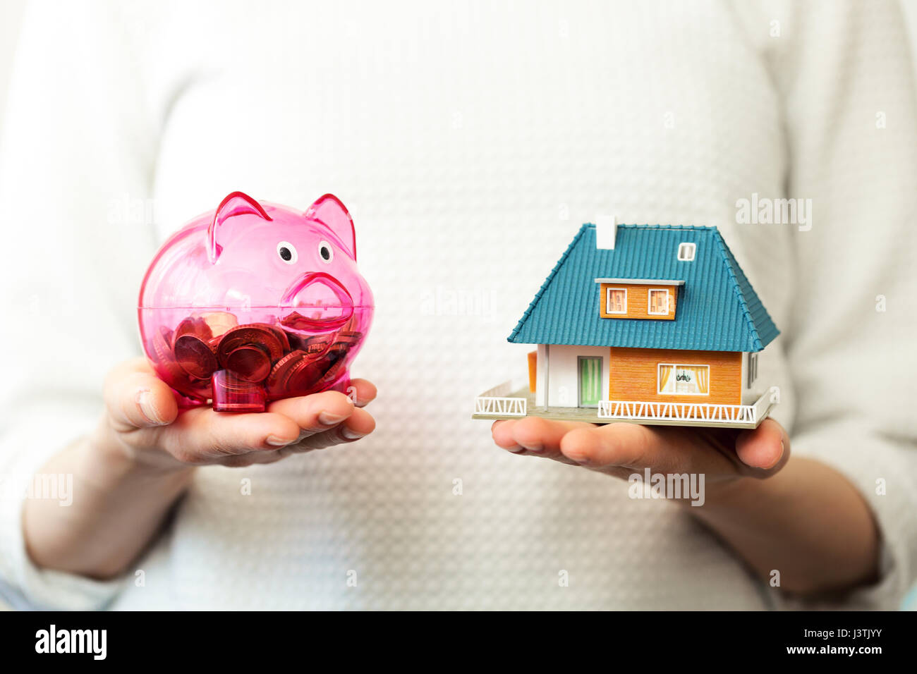 savings for new family house concept - piggy bank and house scale model in hands Stock Photo