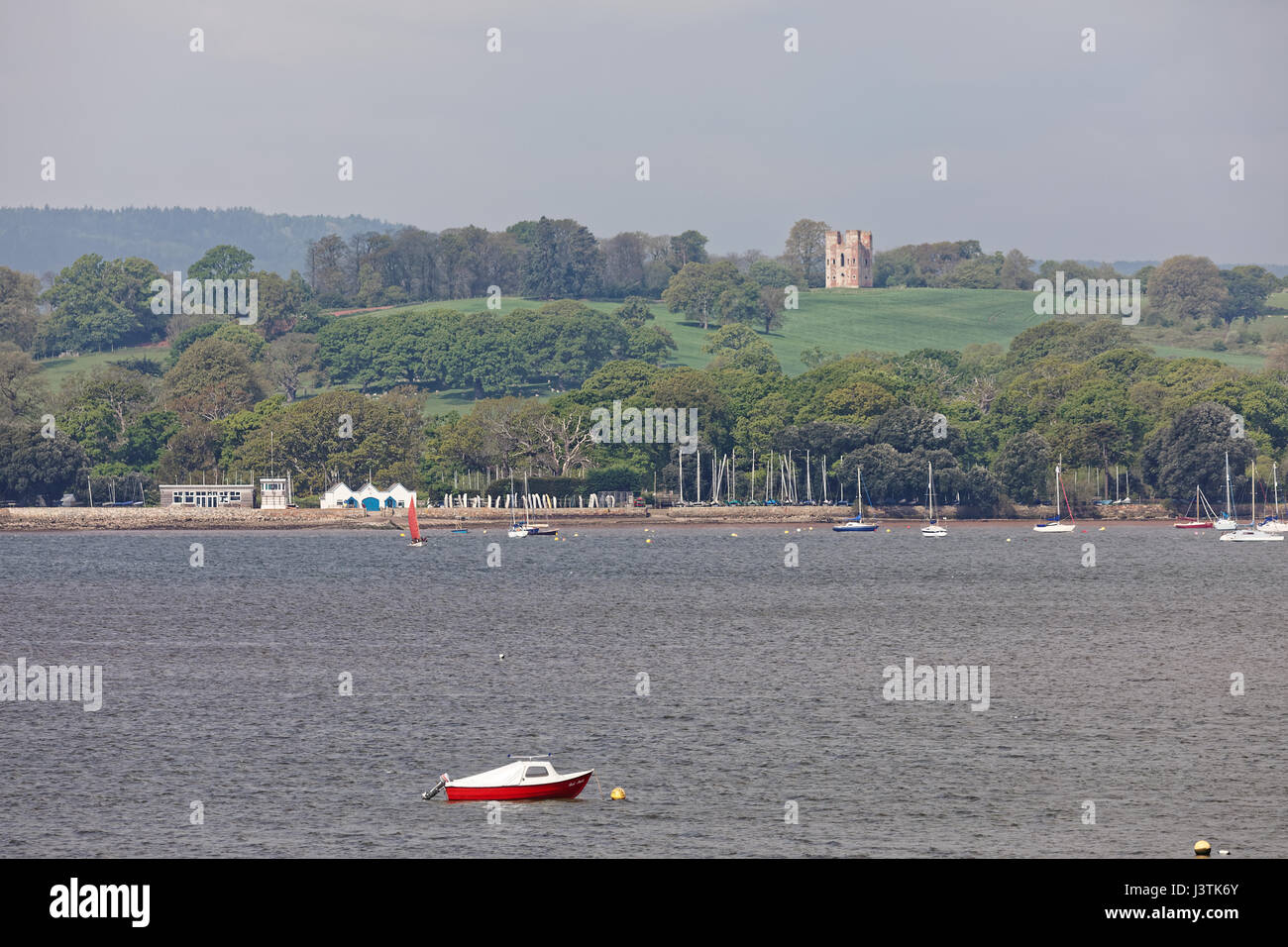 Boats moored in the River Exe estuary with Starcross Yacht Club and Powderham Folly (Belvedere Tower) in the background Stock Photo