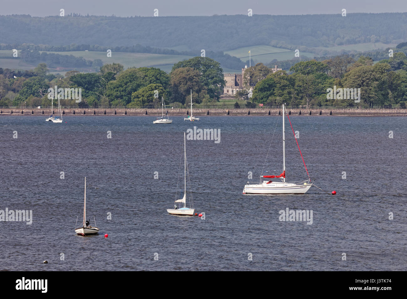 Boats moored in the River Exe estuary with Powderham Castle in the background Stock Photo
