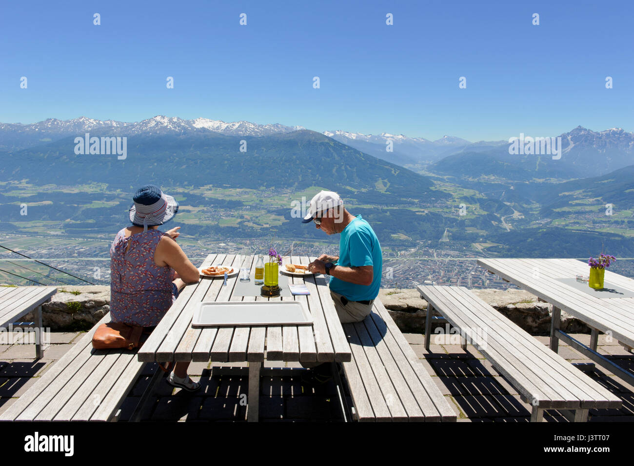 A couple sitting on wooden benches and eating outside the Seegrube Cable Car restaurant, Innsbruck, Tirol, Austria Stock Photo