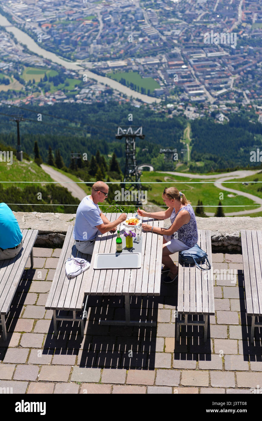 A couple sitting on wooden benches and eating outside the Seegrube Cable Car restaurant, Innsbruck, Tirol, Austria Stock Photo