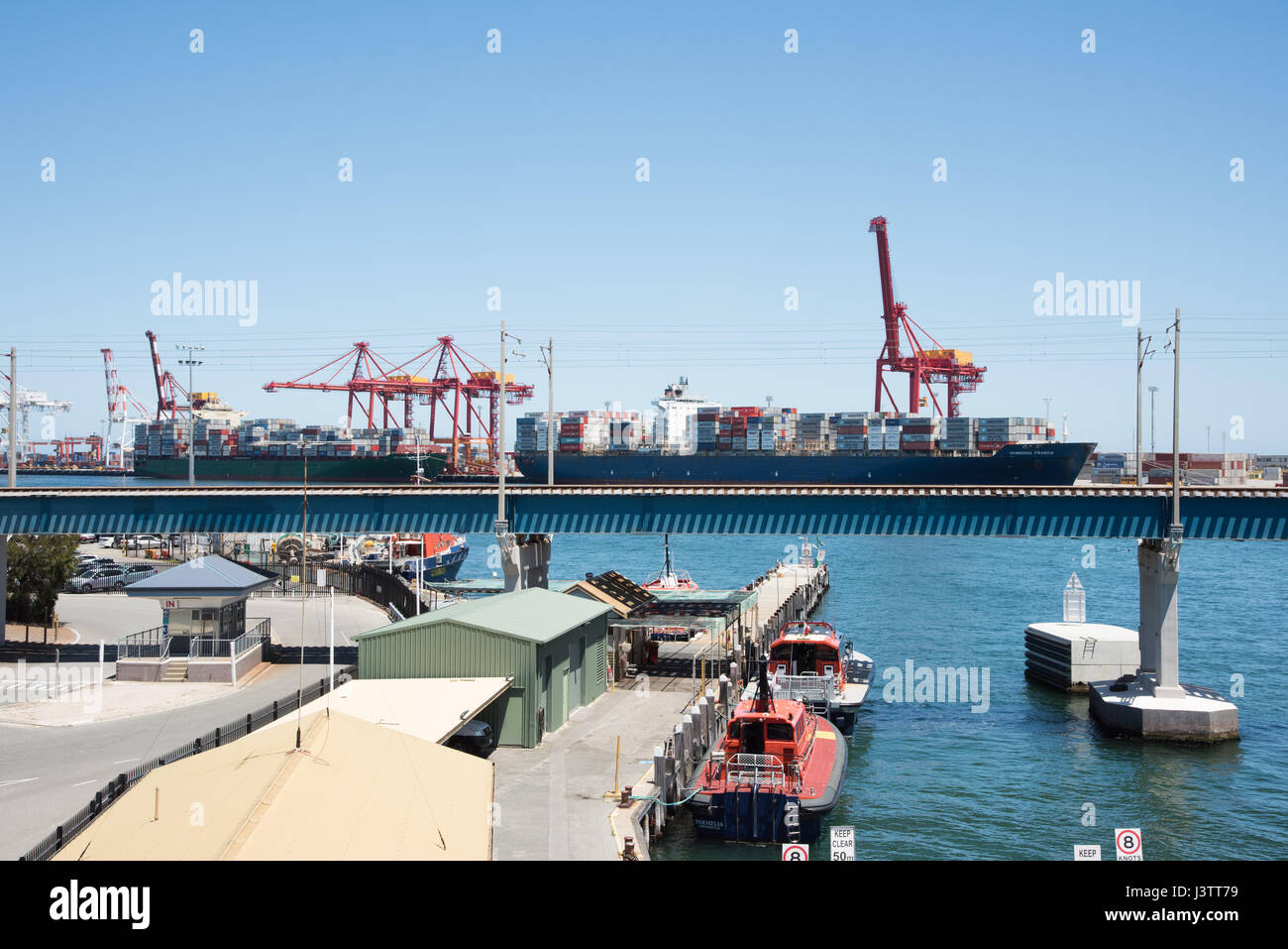 Waterfront dock building, shipping containers, boat and cranes in the commercial port of