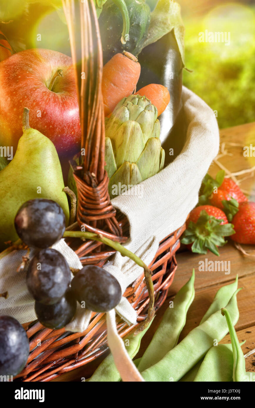 Assortment of fruits and vegetables in a wicker basket on a wooden ...