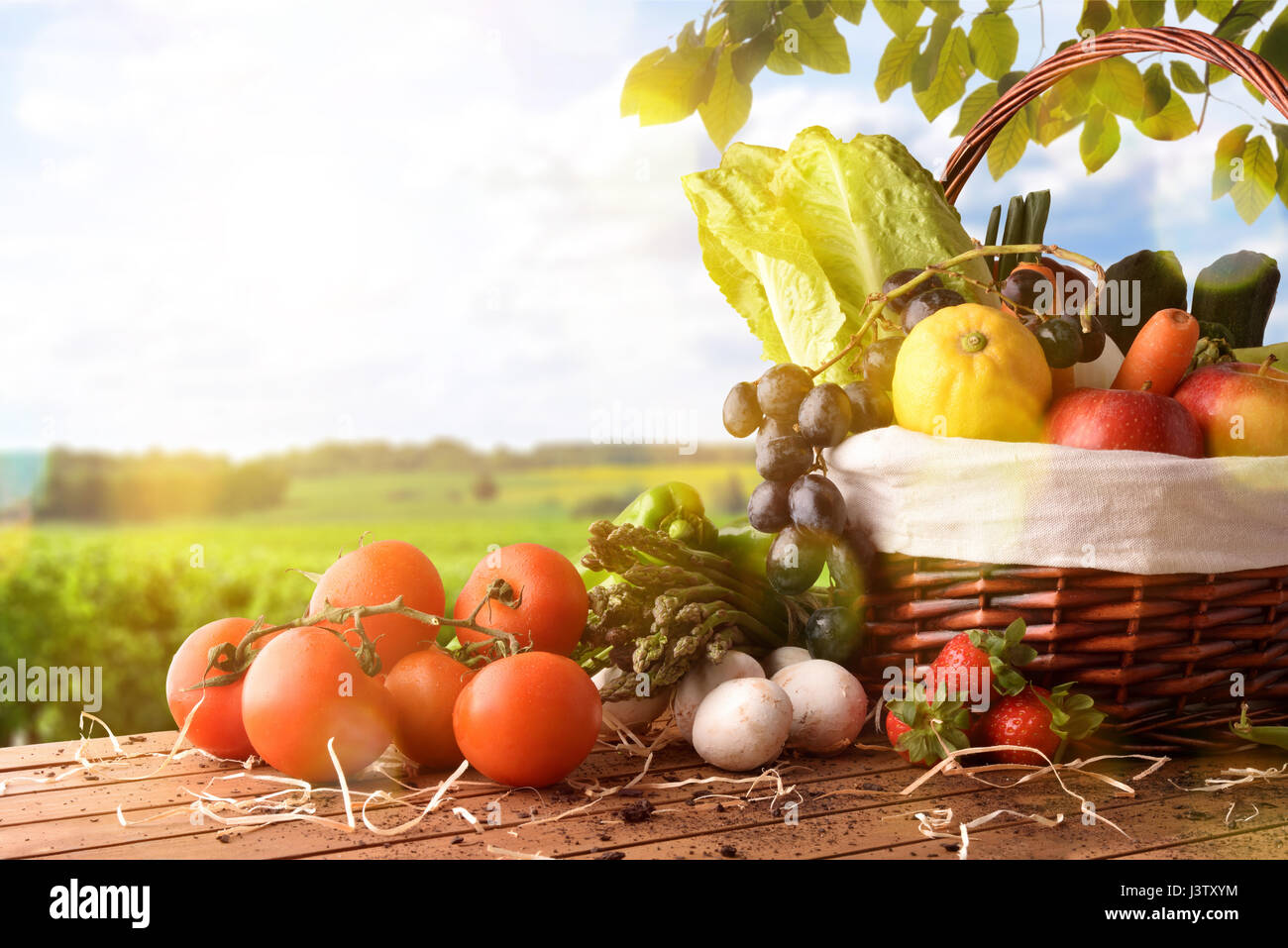 Assortment of fruits and vegetables in a wicker basket on a wooden ...