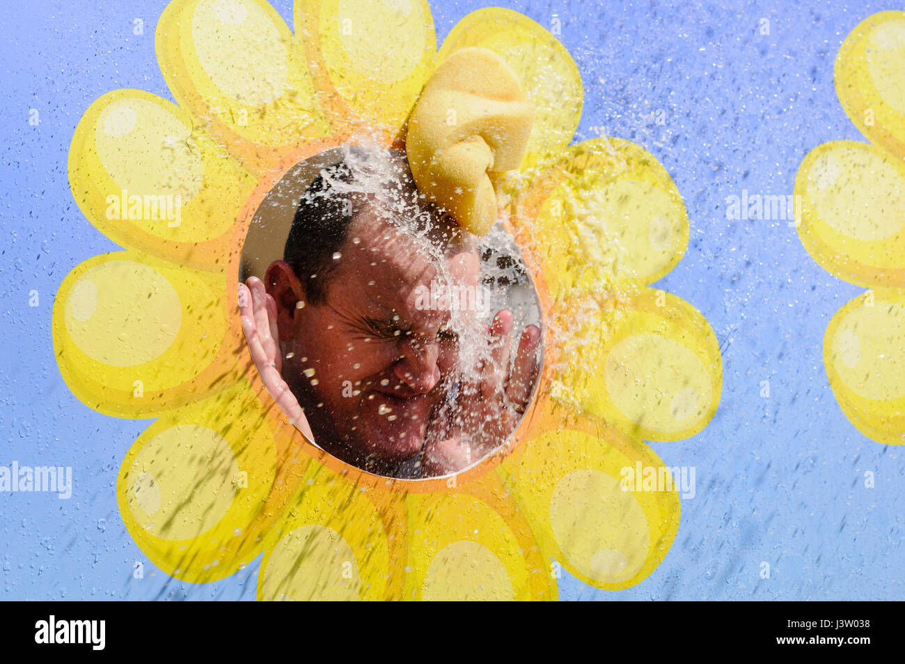 A wet sponge hits a man in the face through a peep board. Stock Photo