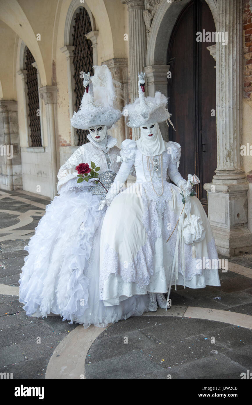 Image of two individuals in complementary swan costumes along the Palace of the Doges during the Carnevale festival in Venice, Italy. Stock Photo