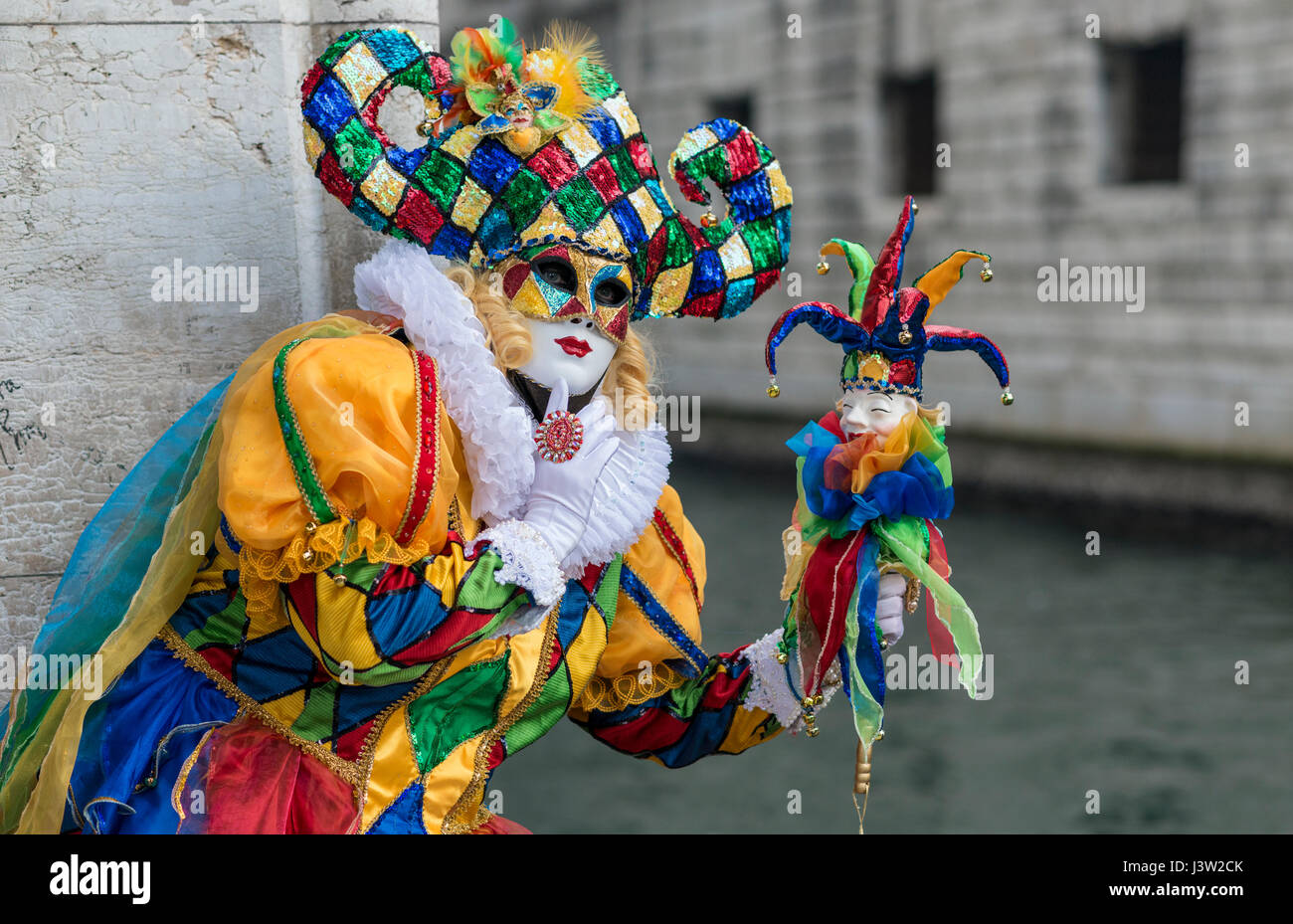 Image of an individual in a colorful costume outside of the Palace of the Doges during the Carnevale festival in Venice, Italy. Stock Photo