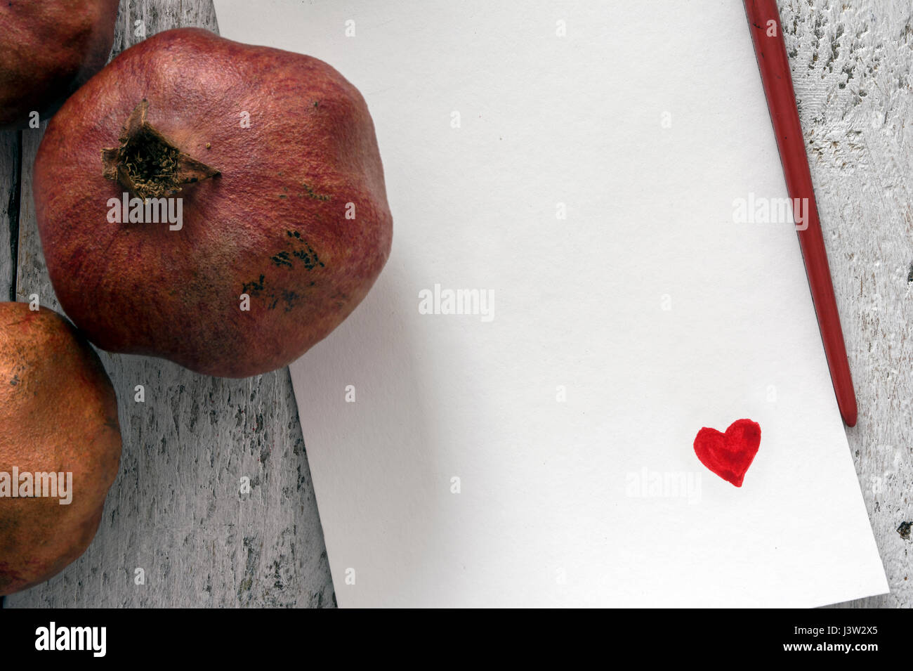 Love note template on white rustic table with pomegranates. Overhead view Stock Photo