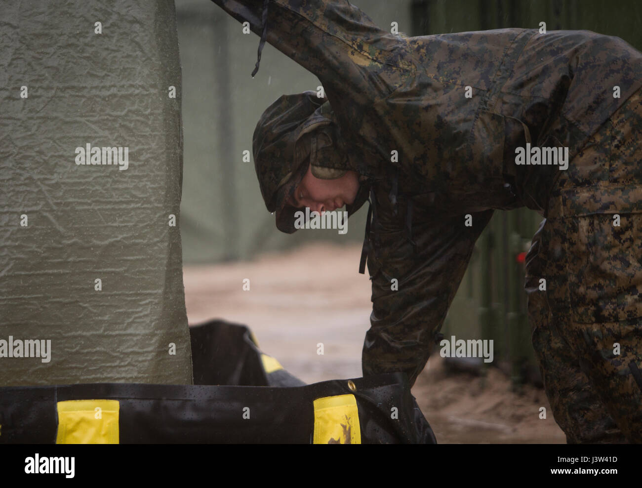 CAMP LEJEUNE, N.C. – Sgt. Andrew C. Mooney, an engineer equipment electrical systems technician with the Combat Logistics Element, Special Purpose Marine Air-Ground Task Force - Southern Command, drains rain water from a spill kit during General Exercise 2 at Marine Corps Base Camp Lejeune, North Carolina, April 24, 2017. The Logistics Combat Element set up camp at Engineer Training Area 2 in order to simulate a schoolhouse construction site in preparation for their upcoming deployment to Central America. (U.S. Marine Corps photo by Sgt. Ian Leones) Stock Photo