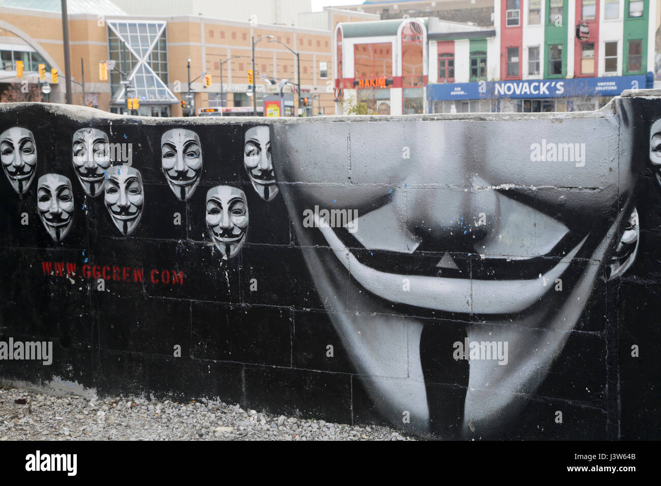 Creepy Faces on Mural Wall with Downtown Retail Buildings in Background, London, Ontario, Canada Stock Photo