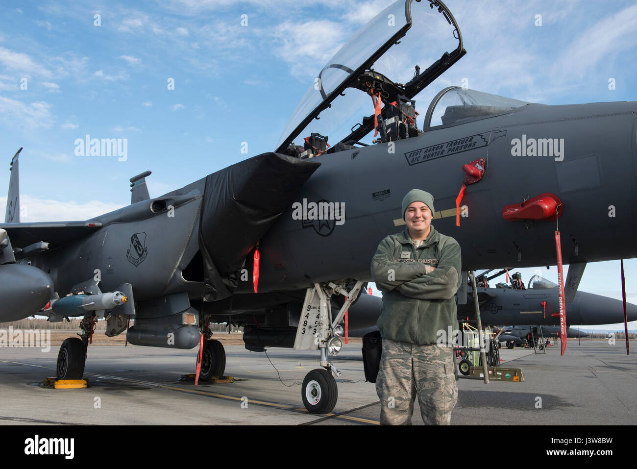 EIELSON AIR FORCE BASE, Alaska – U.S. Air Force Airman 1st Class Ryan Landrum, a 335th Aircraft Maintenance Unit weapons load crew member assigned to Seymour Johnson Air Force Base, N.C., poses for a photo in front of an F-15E Strike Eagle dual-role fighter aircraft from the 335th Fighter Squadron, May 4, 2017 during NORTHERN EDGE 2017 (NE17), at Eielson Air Force Base, Alaska. NE17 is Alaska’s premier joint training exercise designed to practice operations, techniques and procedures as well as enhance interoperability among the services. Thousands of participants from all the services, Airmen Stock Photo