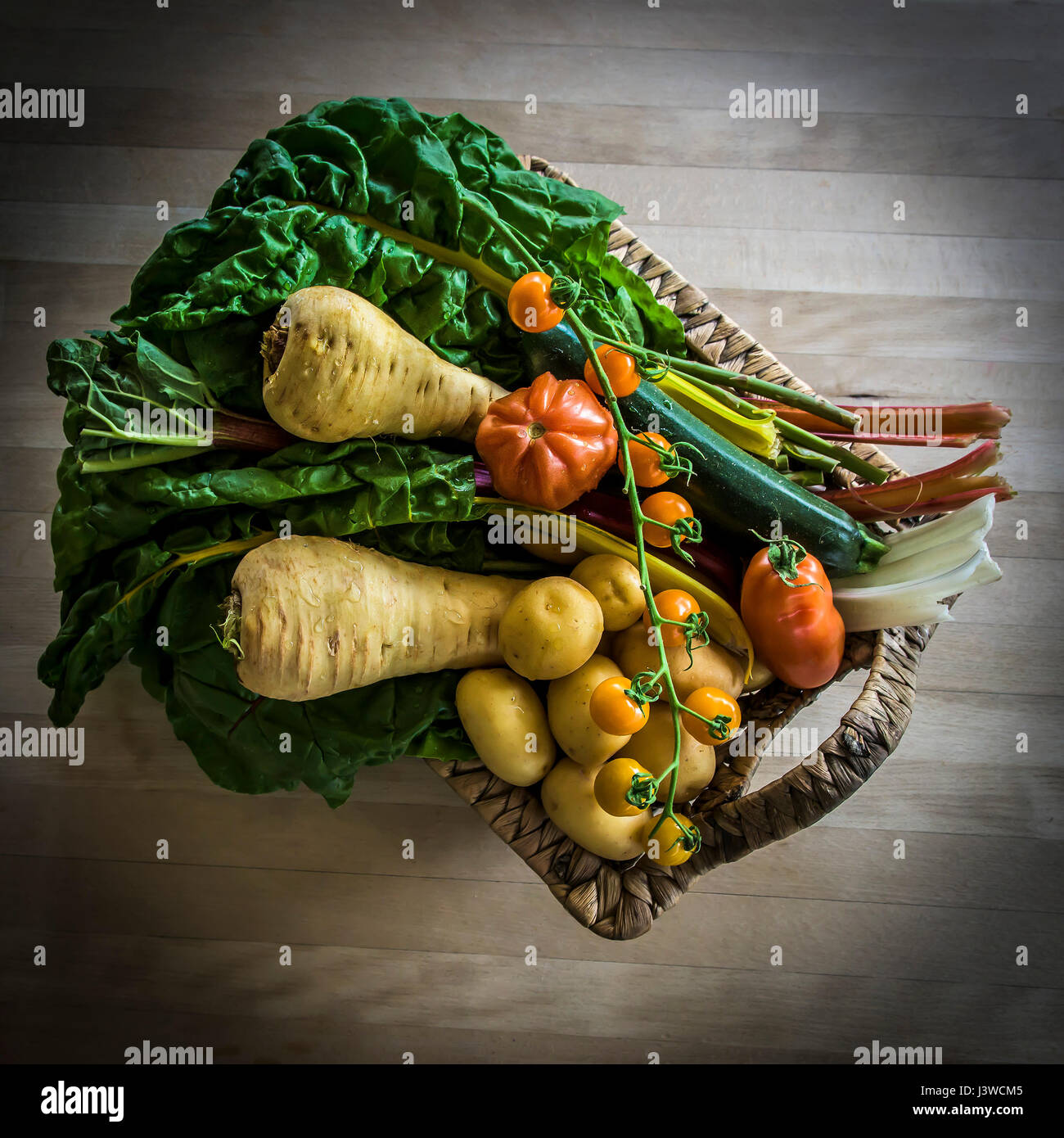 A basket of various fresh vegetables Food Source of nutrition Ingredients Tomatoes Parsnips Potatoes Rainbow Chard Ingredients for cooking Stock Photo