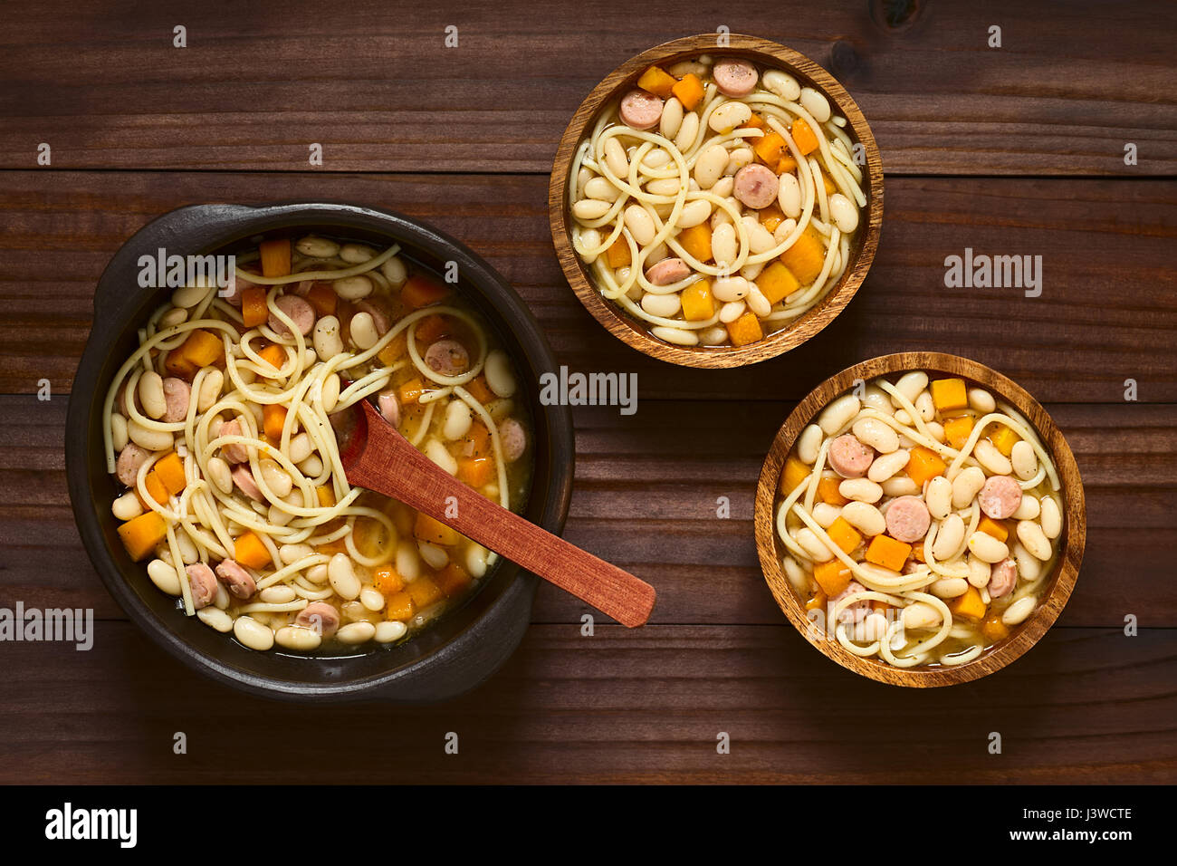 Chilean traditional Porotos con Riendas (beans with reins) dish of cooked dried beans with pumpkin, onion, spaghetti and sausage, in rustic bowls Stock Photo