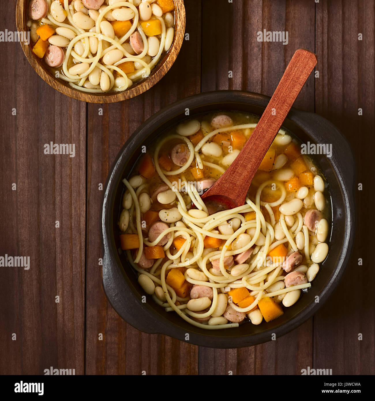 Chilean traditional Porotos con Riendas (beans with reins) dish of cooked dried beans with pumpkin, onion, spaghetti and sausage, in rustic bowls Stock Photo