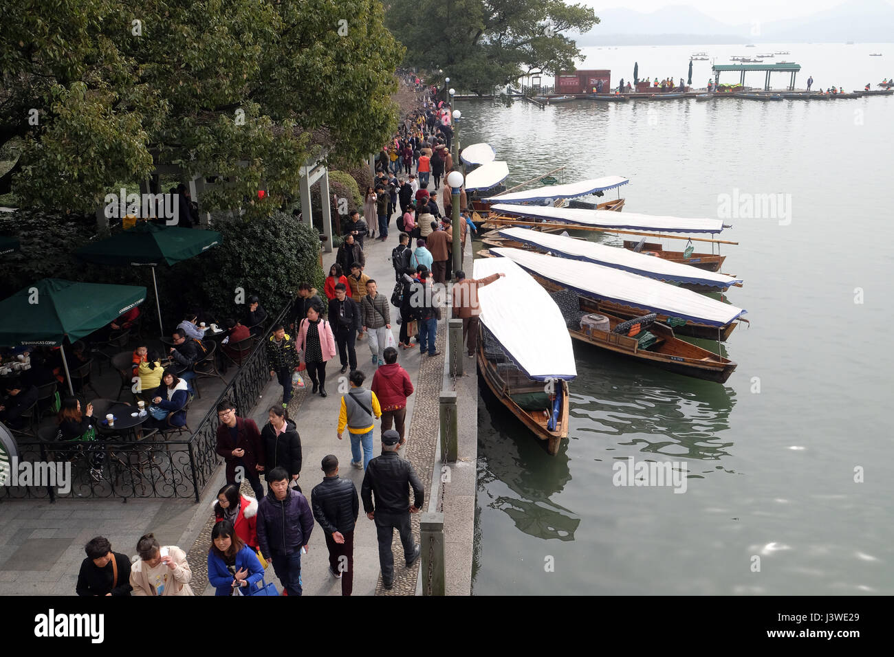 Crowd of tourists and boatmen on West Lake coast, famous park in Hangzhou city, China, February 21, 2016. Stock Photo