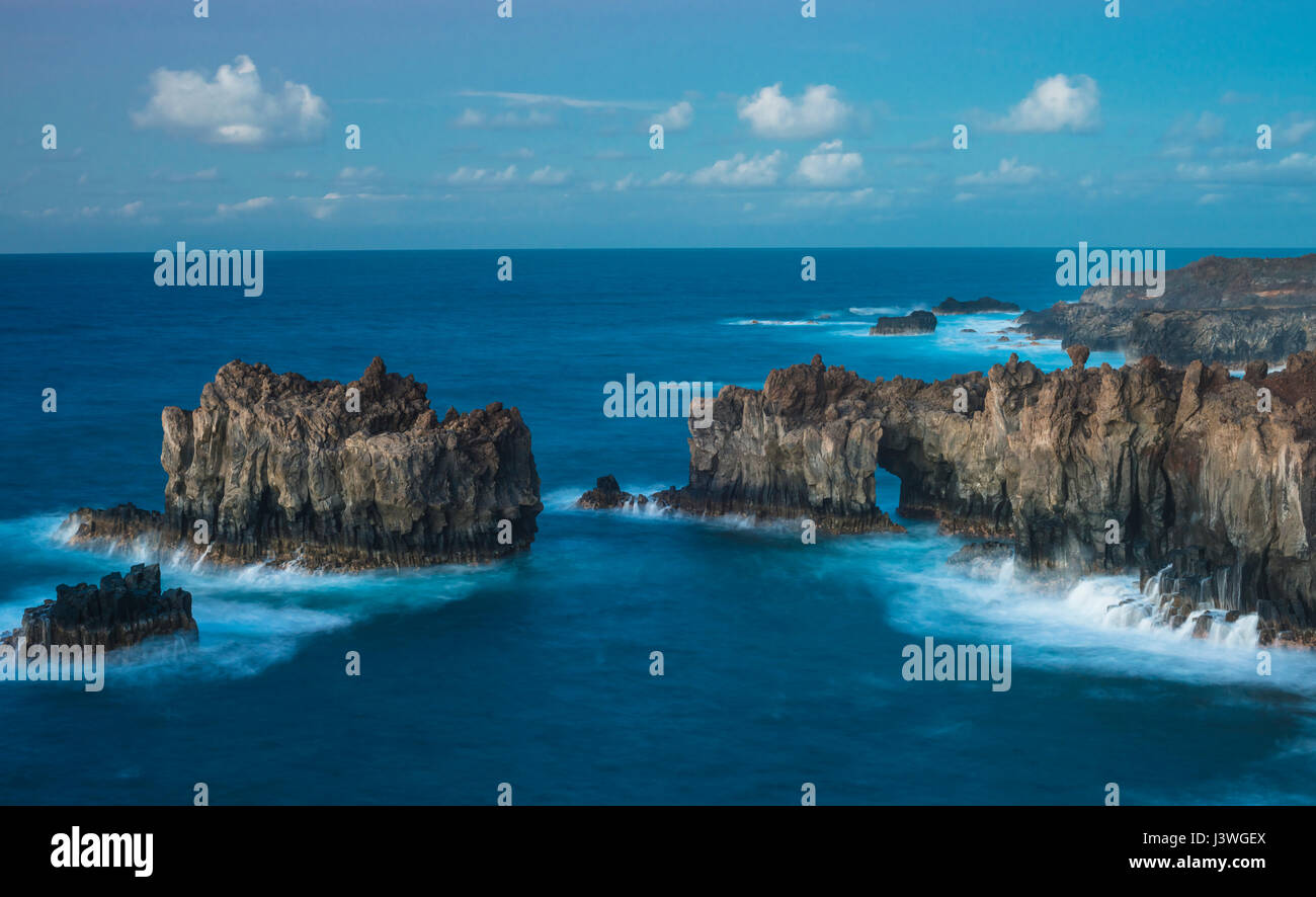 Sea arch and sea stacks of massive and columnar jointed basaltic lava reflecting the power of the Atlantic Ocean, La Dehesa, western El Hierro Stock Photo