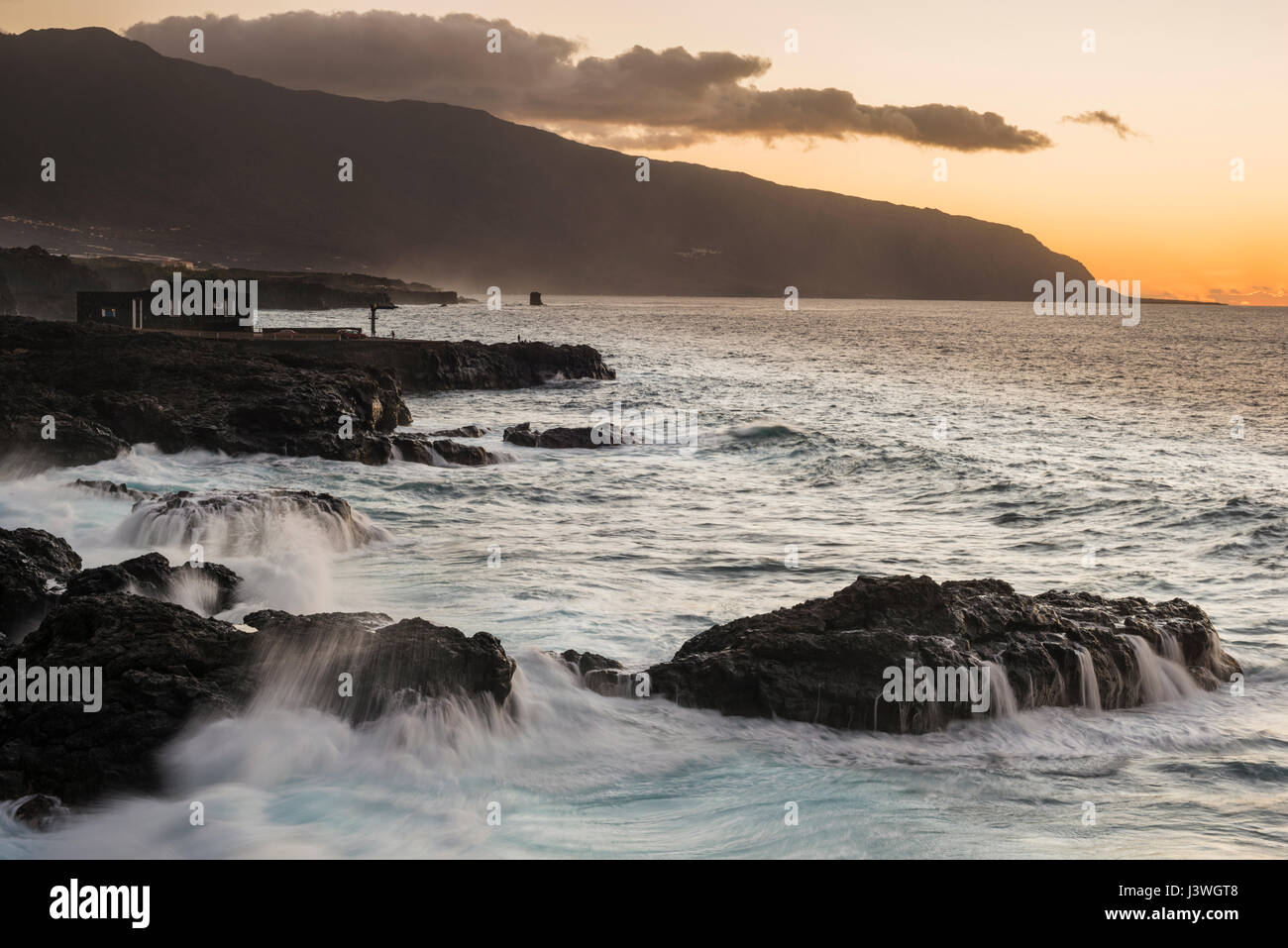 Sunset across the massive El Golfo collapse embayment, with columnar jointed lavas in the sea in foreground, from Las Puntas, El Hierro, Stock Photo