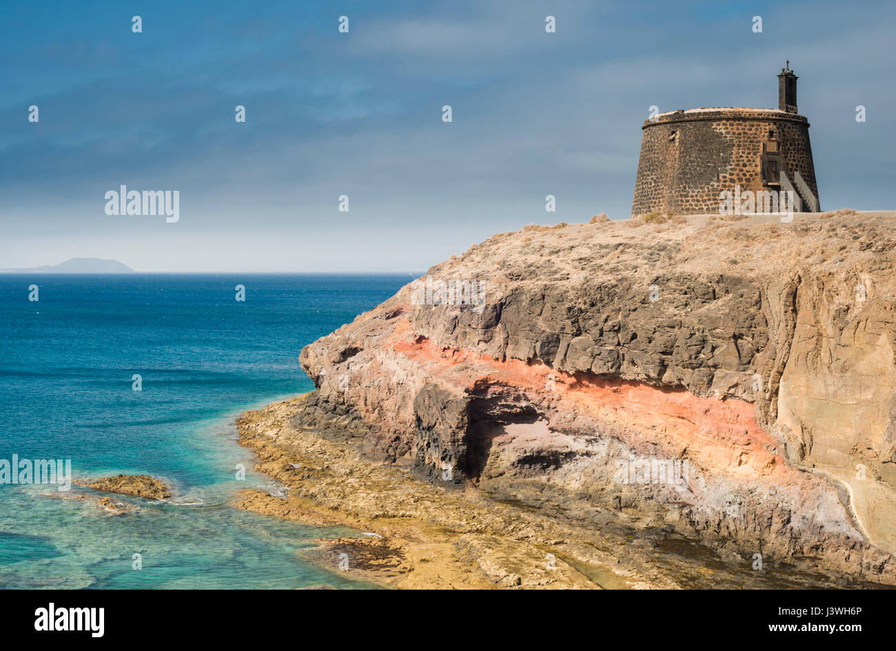 Castillo de las Coloradas on the cliffs east of Playa Blanca, Lanzarote, with the island of Fuerteventura in the distance Stock Photo