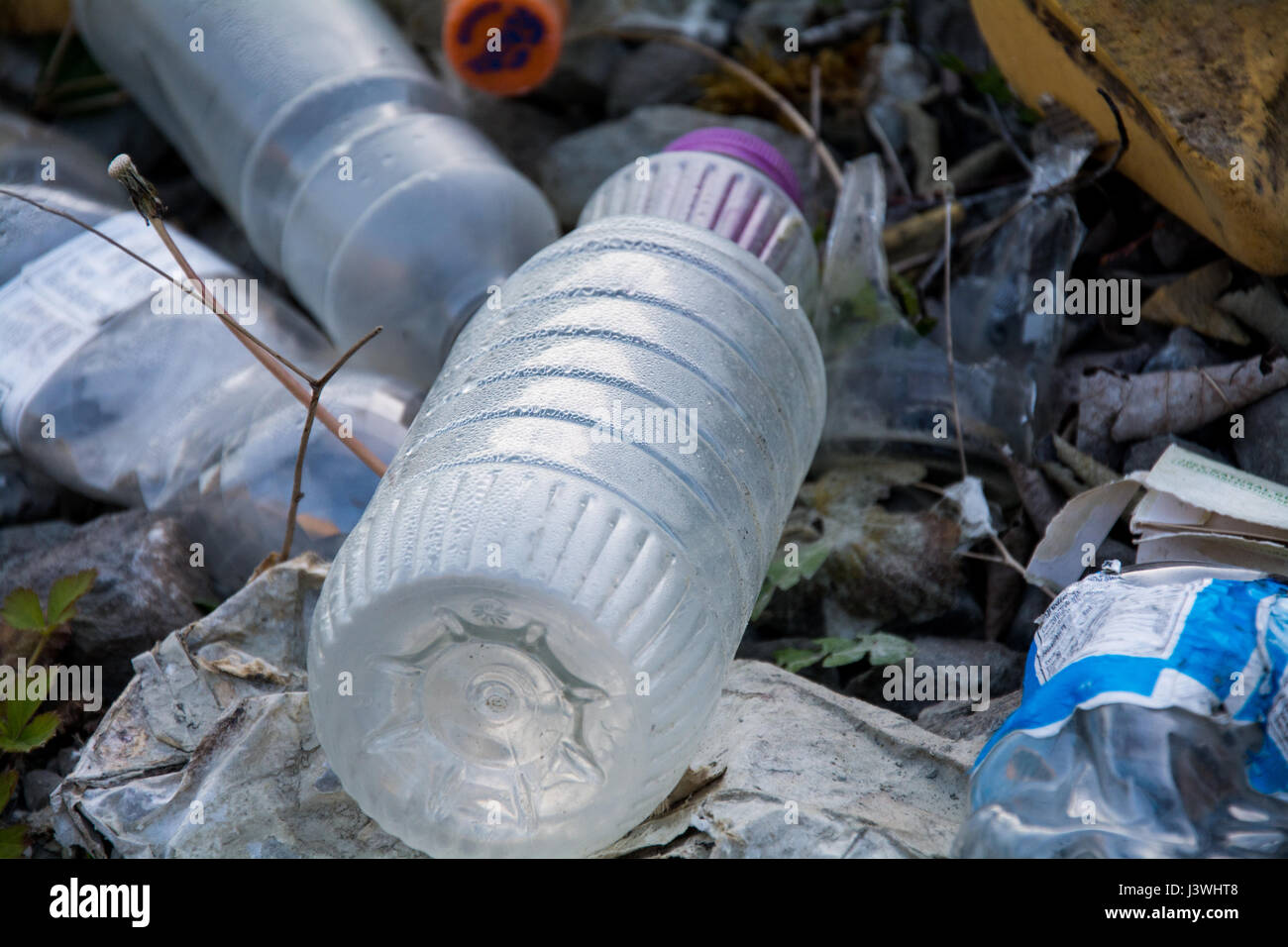 An image of rubbish that's been fly tipped, with the focus on an empty drinks bottle. It represents environmental issues such as plastic pollution. UK Stock Photo