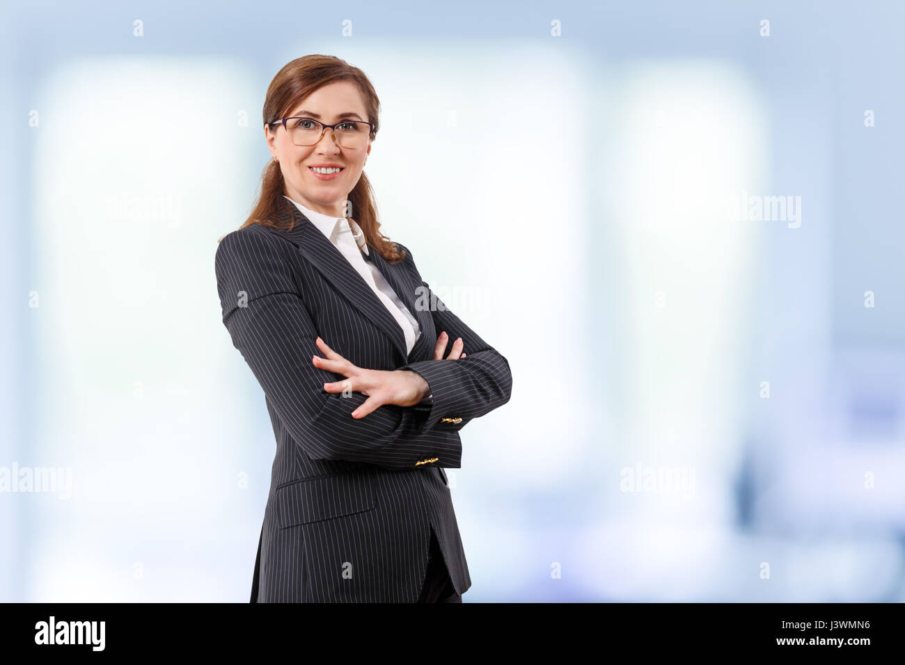 Portrait of a beautiful businesswoman 50 ears old in crossed arms pose in the office. Stock Photo