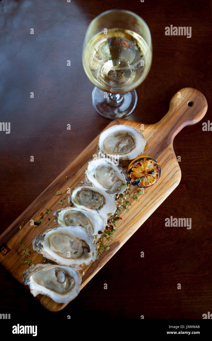 Food Raw oysters on a half shell with a glass of white wine with herbed salt sprinkled on the oysters Williamsburg Virginia VA Waypoint Restaurant Stock Photo